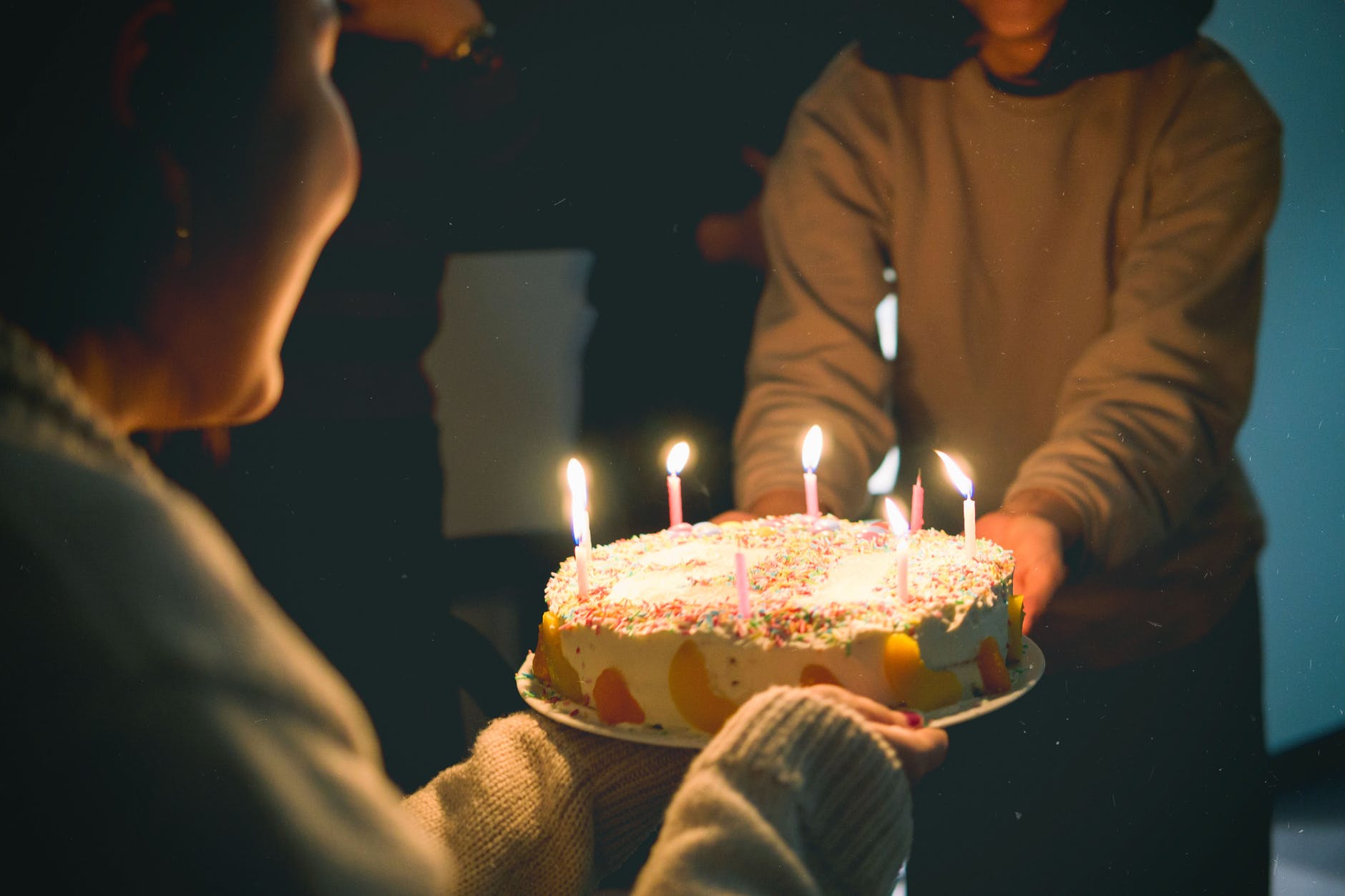 A person handing a birthday cake to another.