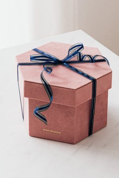 A pink, hexagonal gift box with a blue ribbon.
