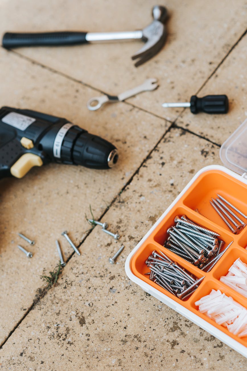 A toolbox with various tools, nails, and screws on the ground.