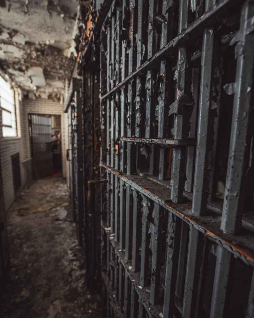 The iron bars of a prison cell in an old hallway. Photo by Cameron Casey on www.pexels.com