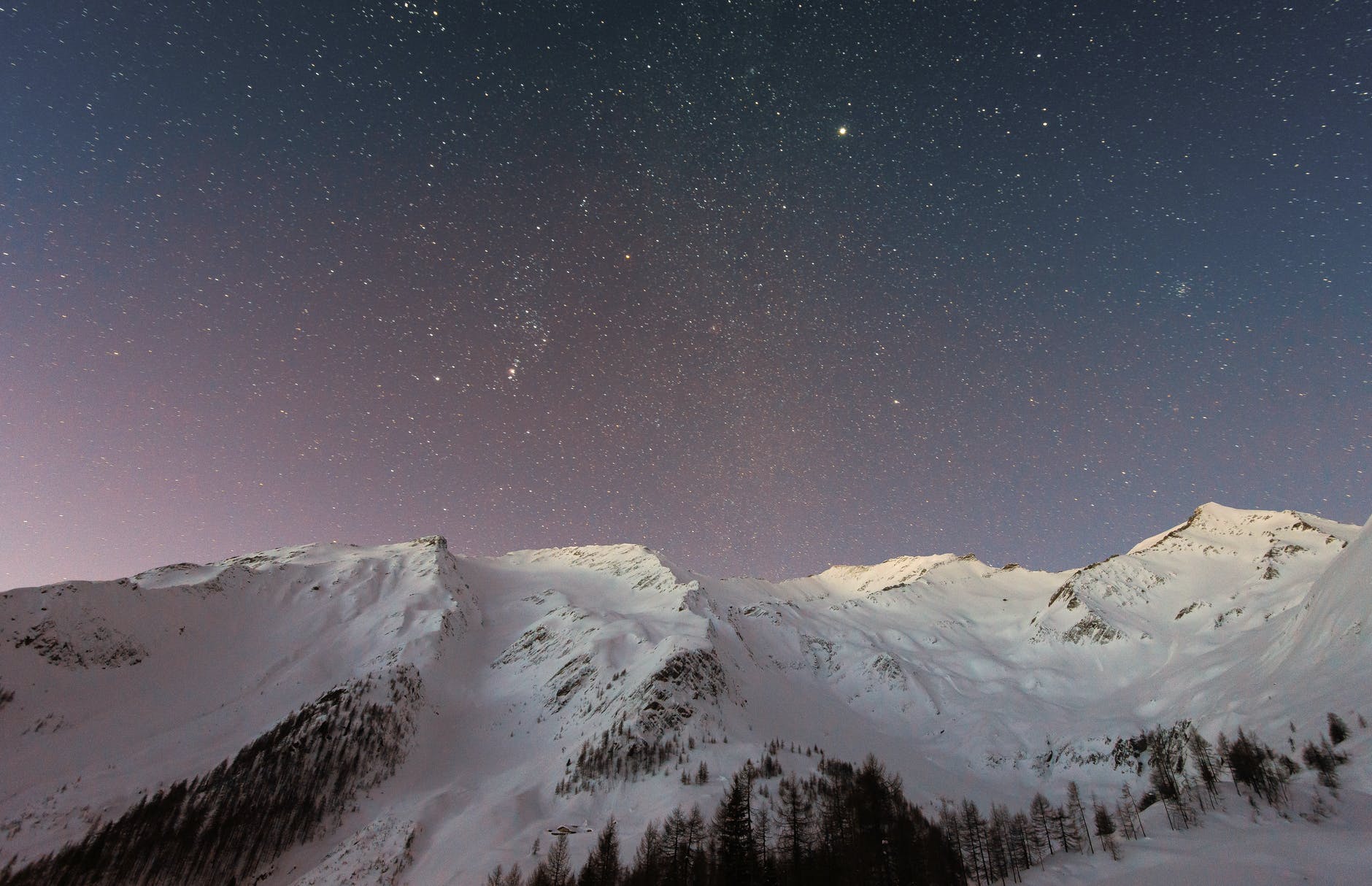 A sky full of stars above some snowy mountains. Photo by eberhard grossgasteiger on pexels.com