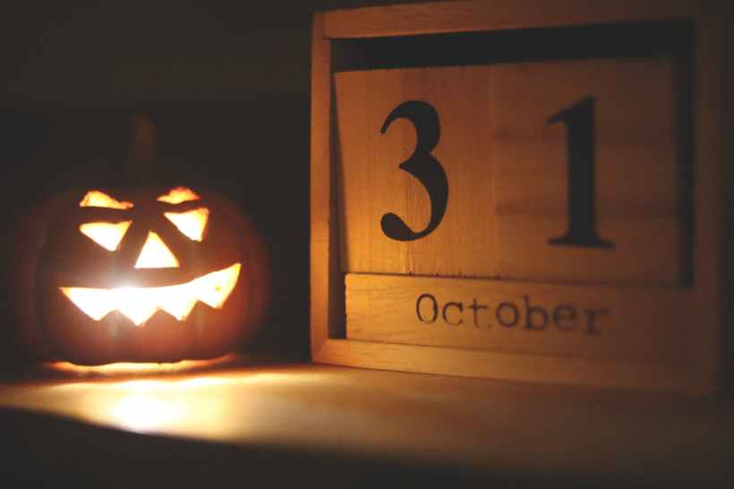 A jack-o-lantern next to a wooden daily calendar indicating October 31.