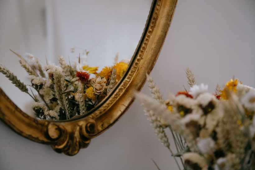 A vase of flowers reflecting in a mirror.