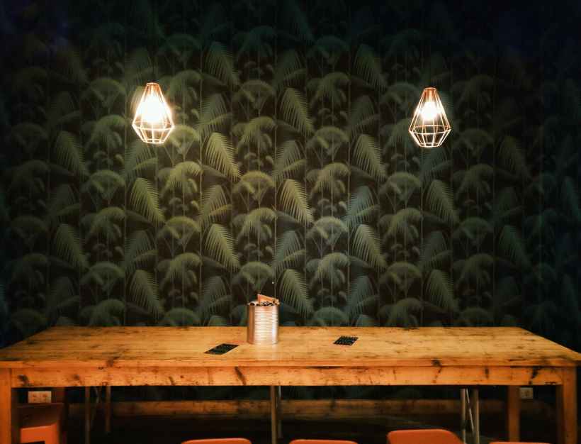 A restaurant table against a wall with green patterned wallpaper.