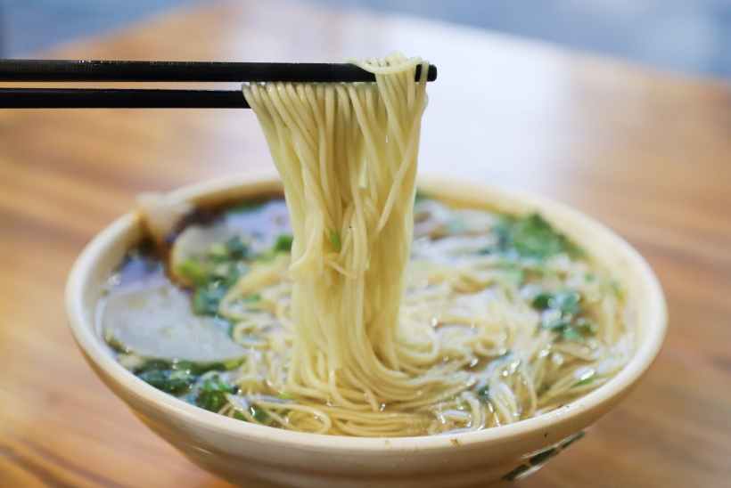 A bowl of East Asian noodle soup, with chopsticks.