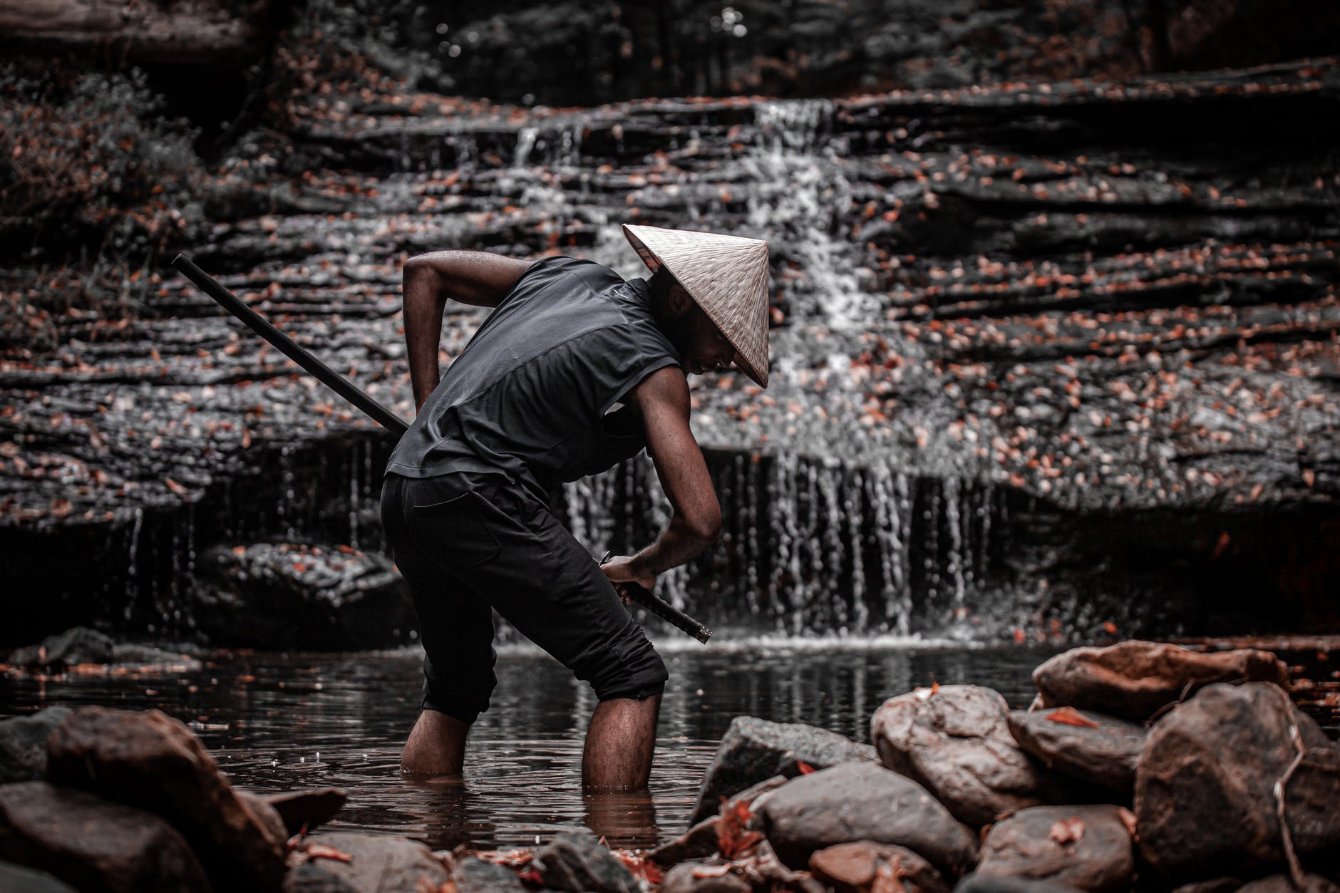 A man dressed as a samurai, in front of a waterfall.