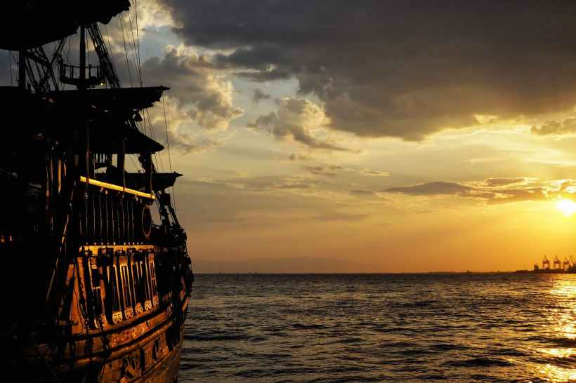 A pirate ship against a sunset sky.