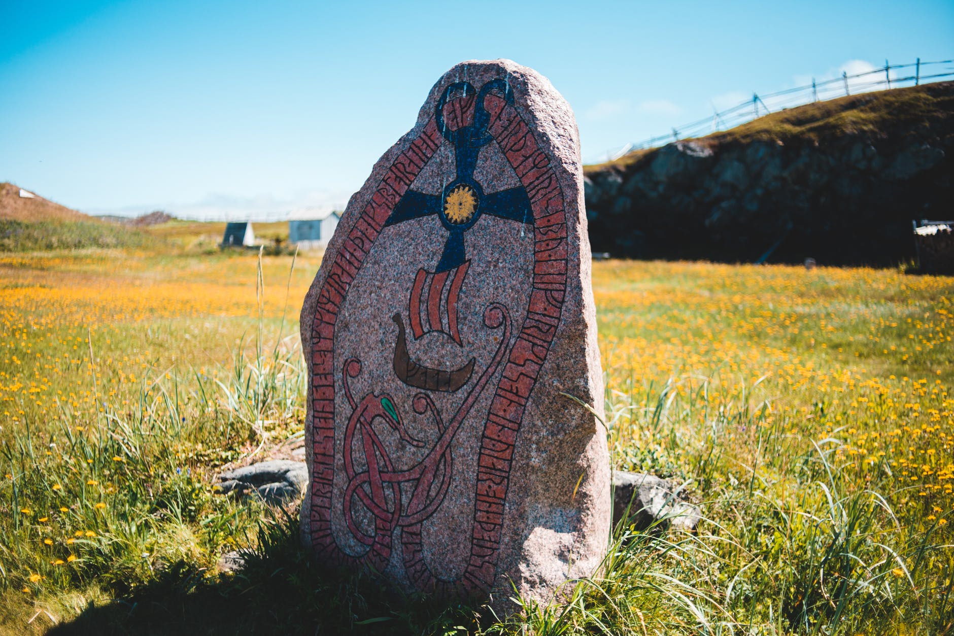 A painted runestone in a field.