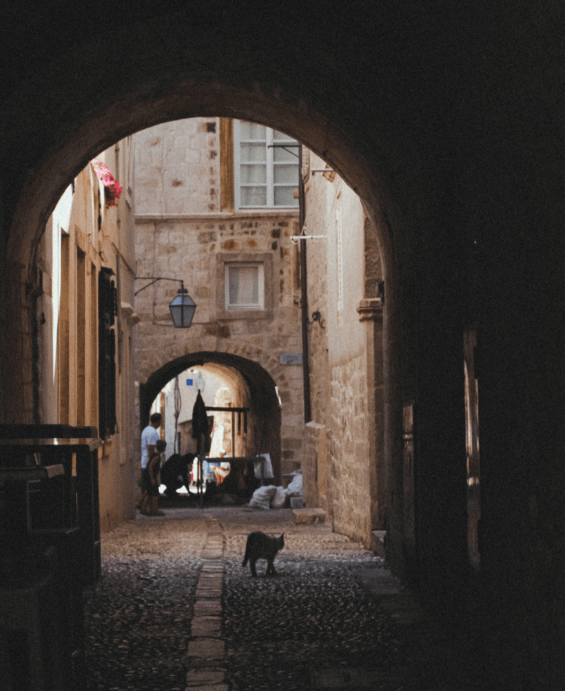 A cobblestone alley seen through an arc. Photo by Anfisa Eremina from Pexels.