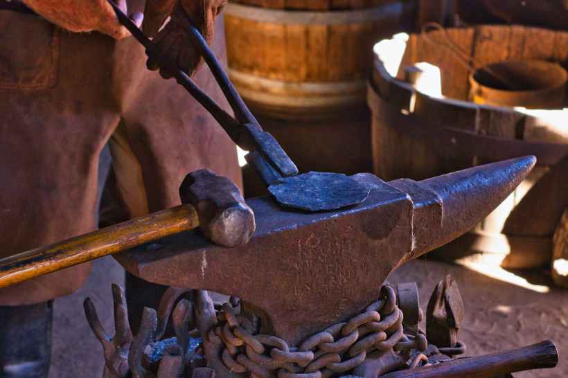 Metal being held on an anvil with tongs.