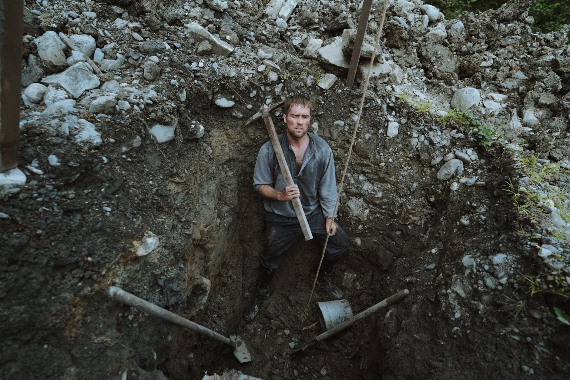 A tired man at the bottom of a freshly-dug hole.