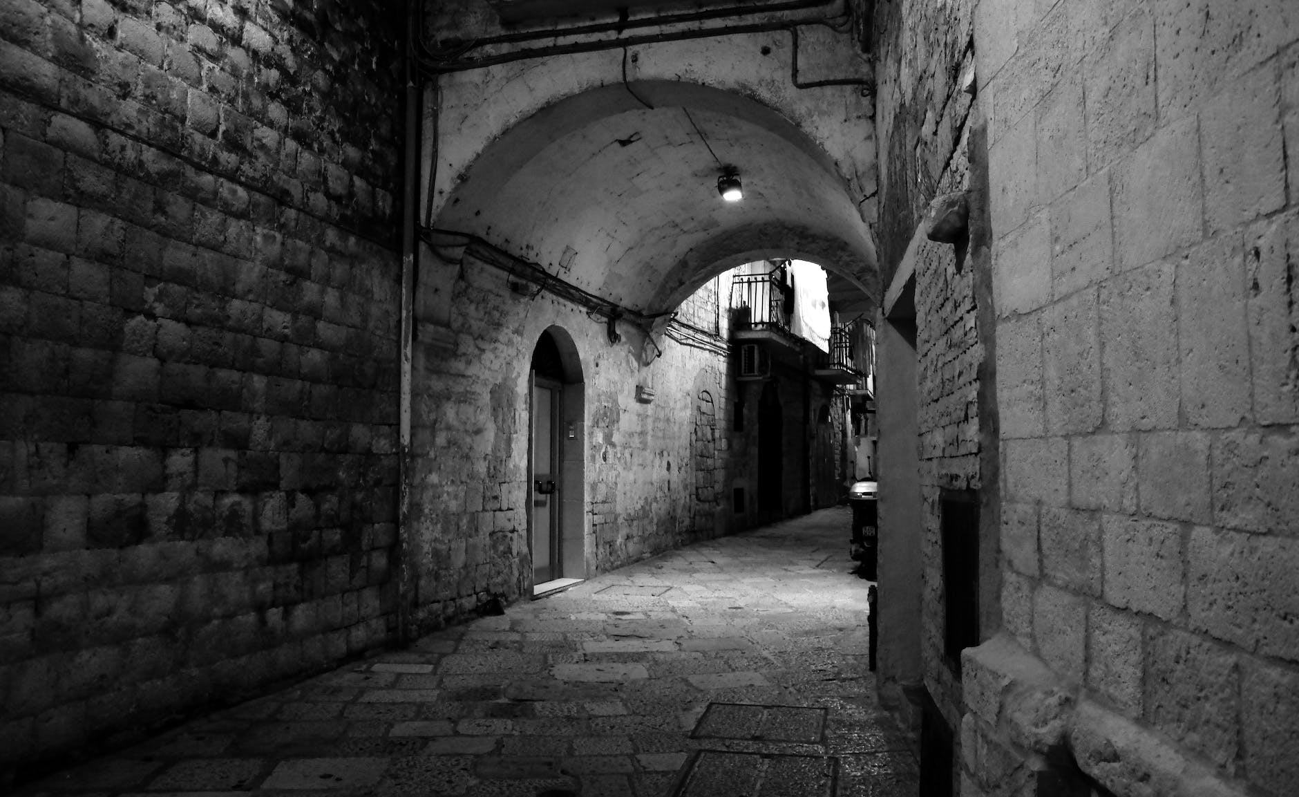 A black and white photo of an arch in an alley.