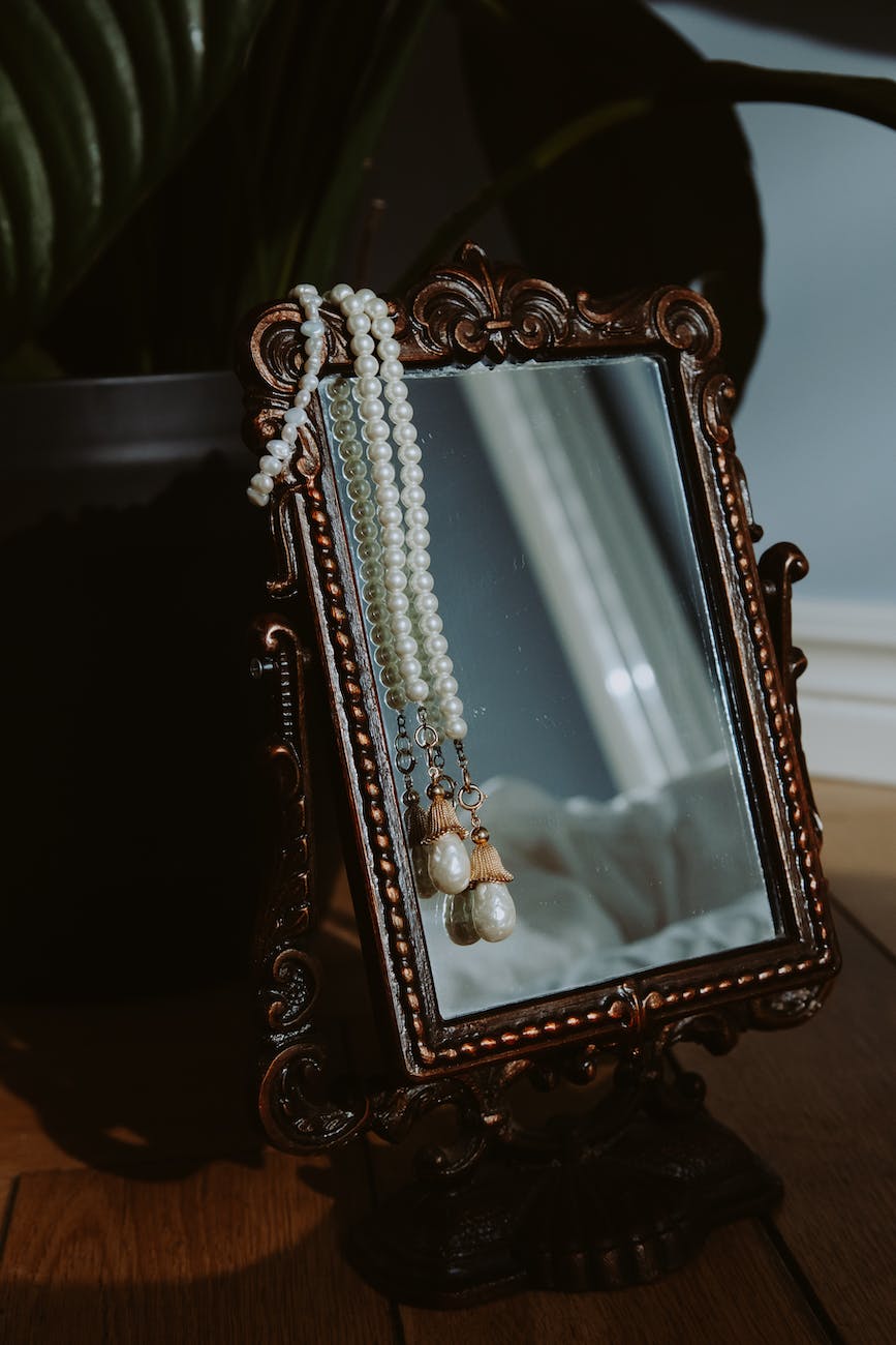 A mirror with pearl necklaces draped over it.