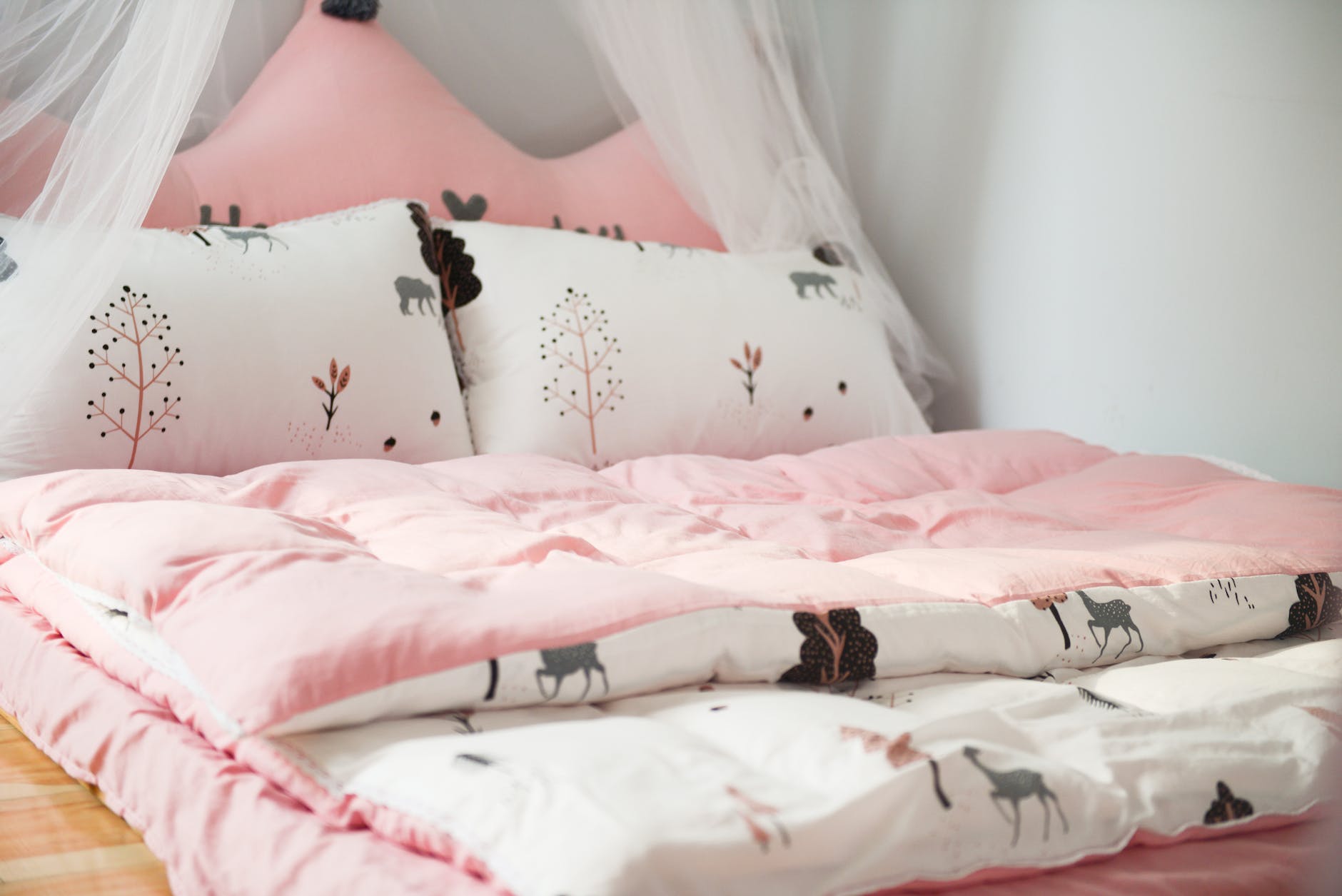 A bed with pink and white sheets.