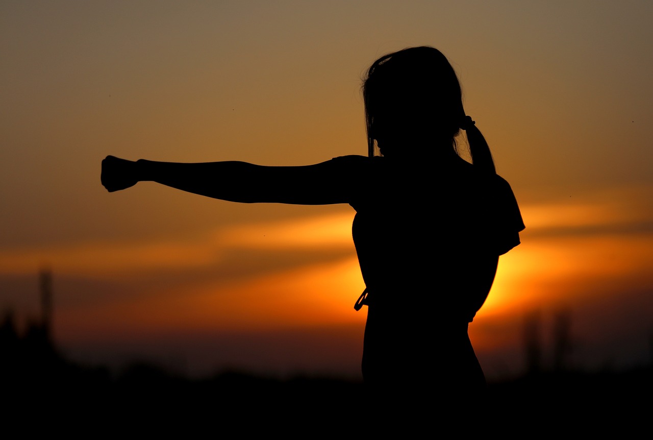 A woman in silhouette doing martial arts in front of the sunset.Image by svklimkin from Pixabay