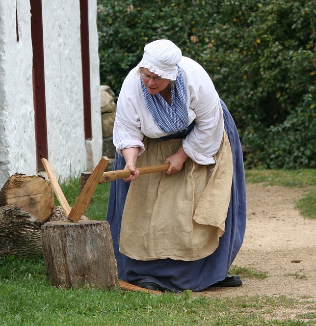 A female historical reenactor chopping wood.