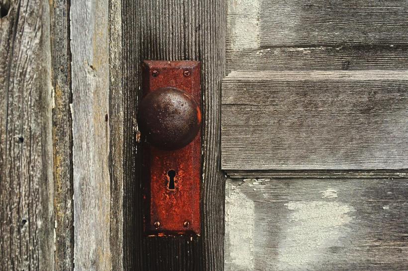 The doorknob and keyhole on a wooden door.
