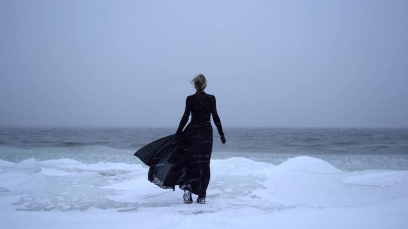 A woman standing on an icy beach.