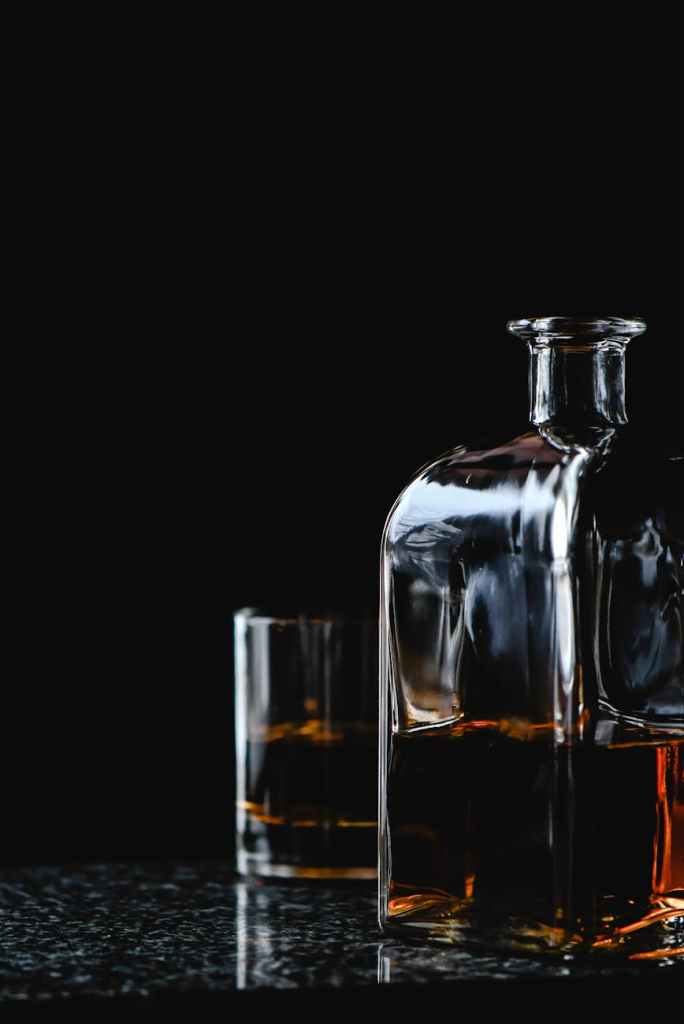 A decanter and glass of brown liquor.