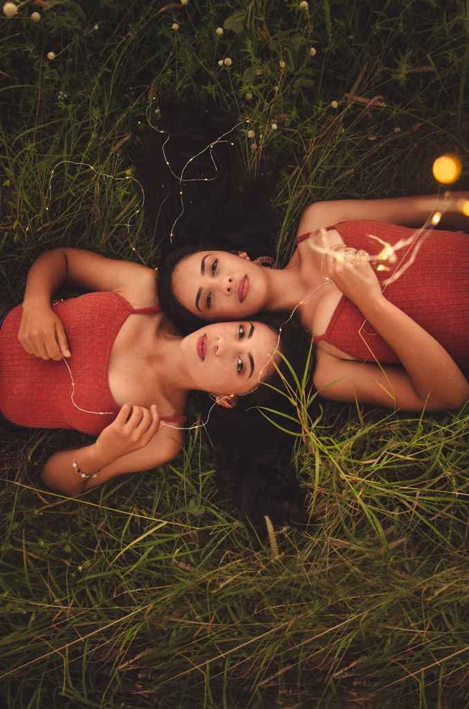 Two sisters lying on grass.