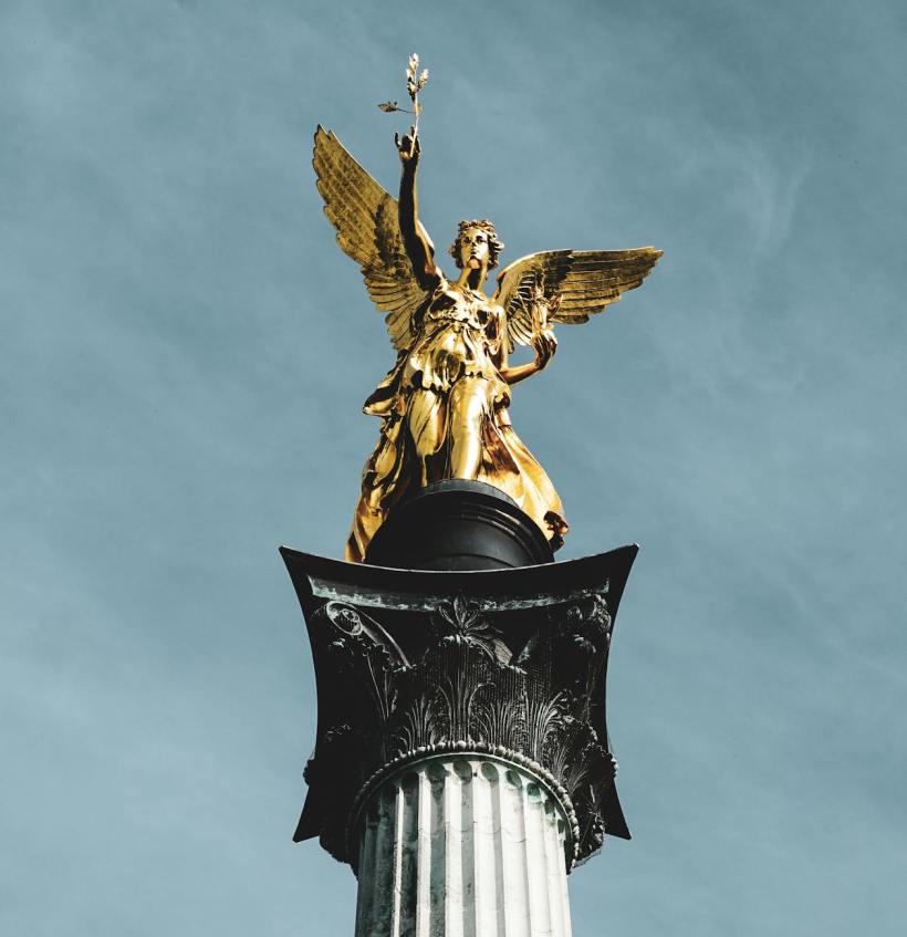 The top of a victory monument with a golden statue.