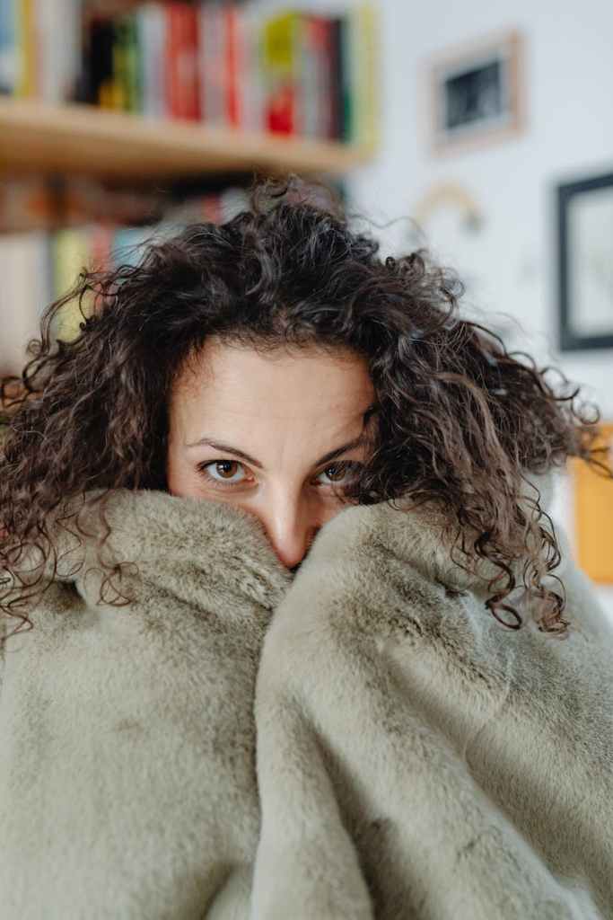 A woman with a furry blanket pulled up to her nose.