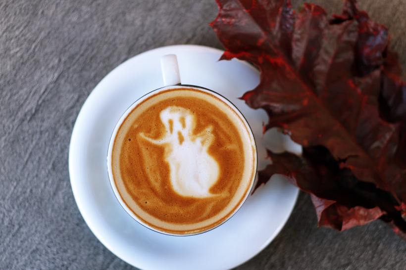 An autumn-themed coffee with a ghost drawn in the foam.