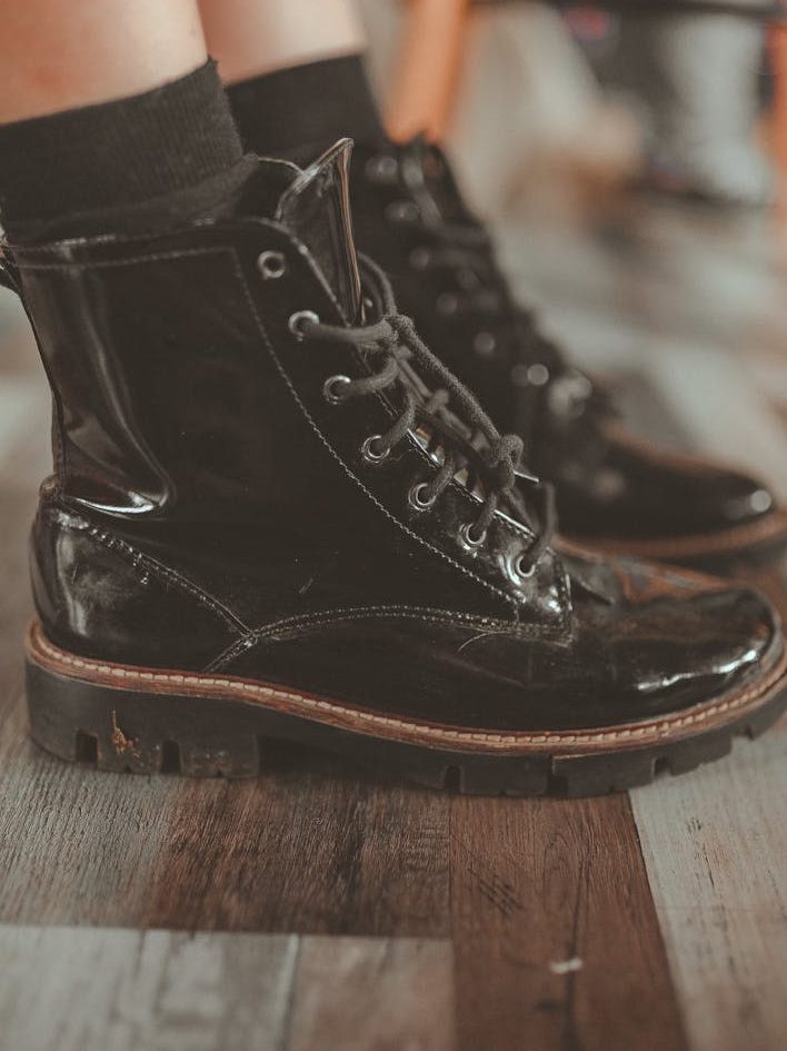 Feet wearing leather boots on a wooden floor.