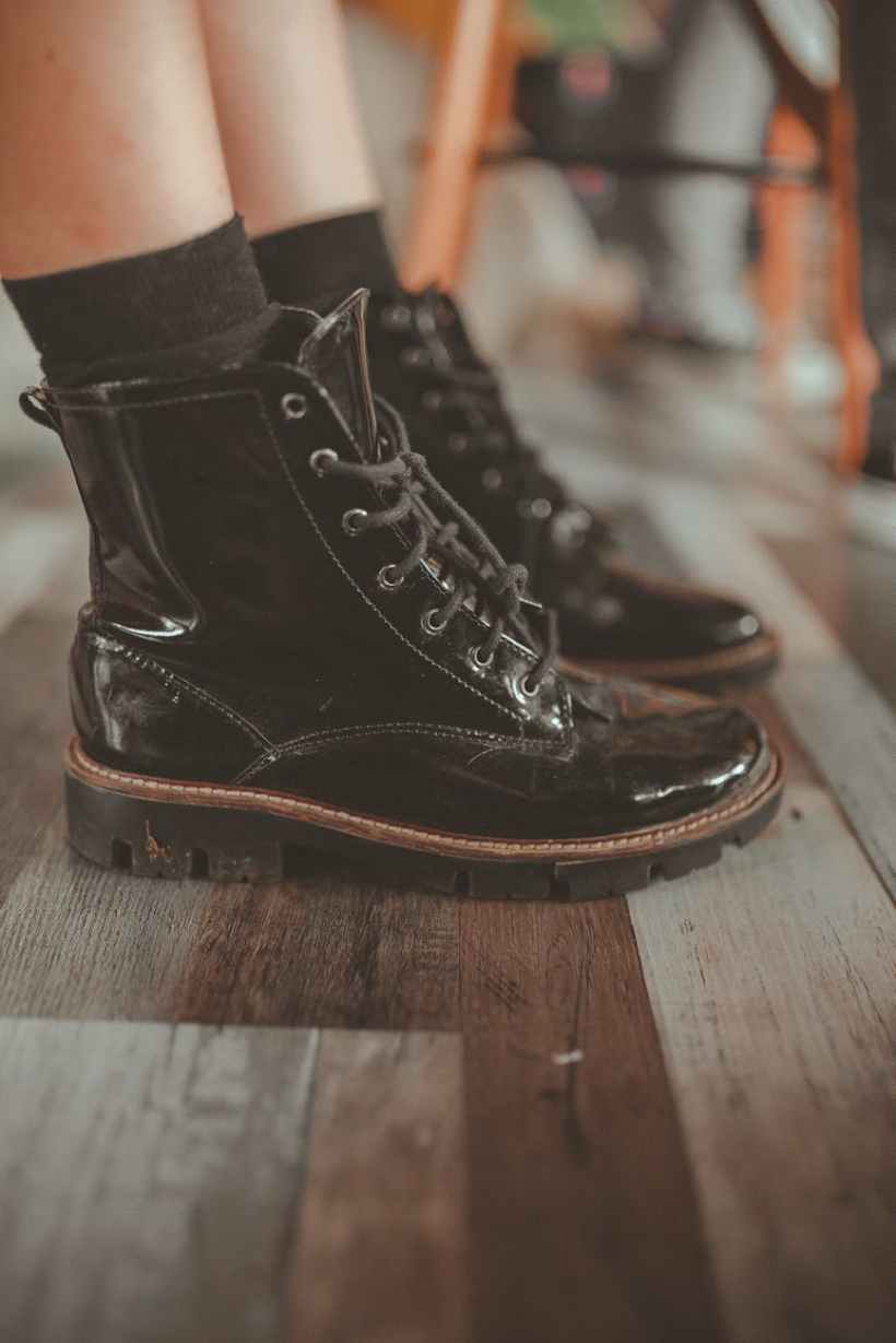 Feet wearing leather boots on a wooden floor.