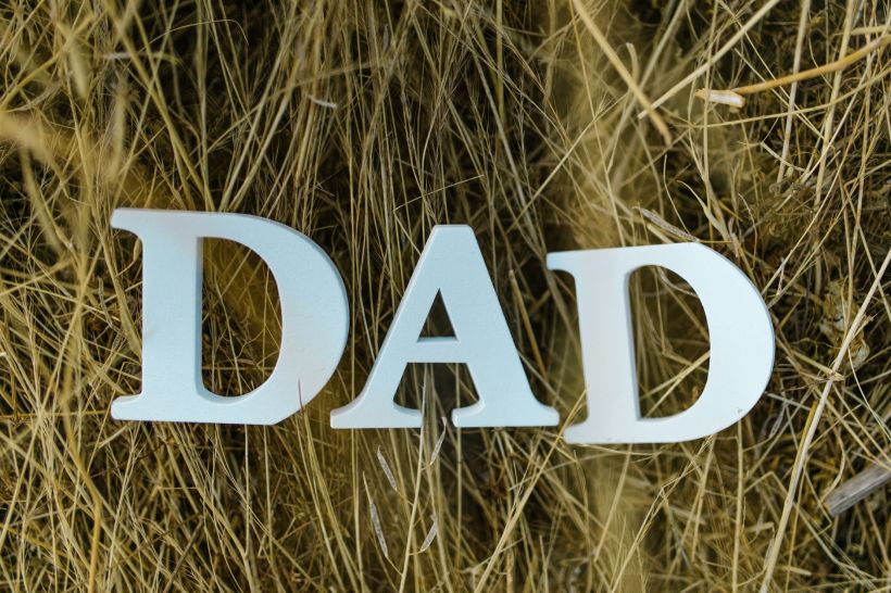 The word Dad spelled with wooden letters on a grass background