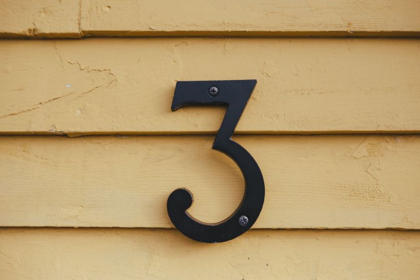The number three mounted on the wall of a house.