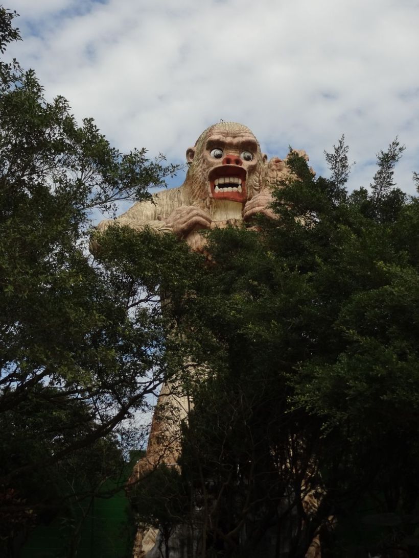 A large statue of Bigfoot over some trees.